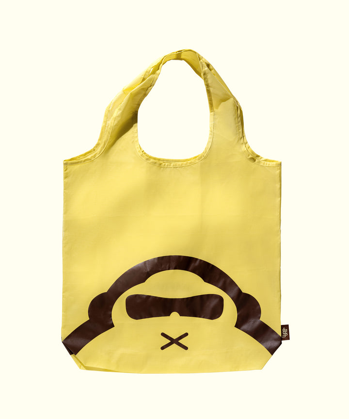 Yellow reusable shopping bag with fun graphic of a monkey face in sunglasses, perfect for getting organized daily. Sun Bum.