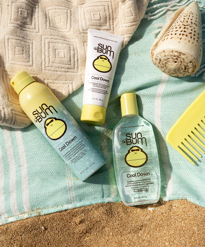 Sun Bum After Sun Cool Down Lotion products on a beach towel with a shell and a yellow comb, Sun Bum.