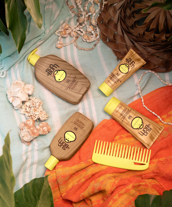 Original SPF 50 Sunscreen Lotion by Sun Bum displayed with beach-themed accessories including shells, a yellow comb, and a woven basket.