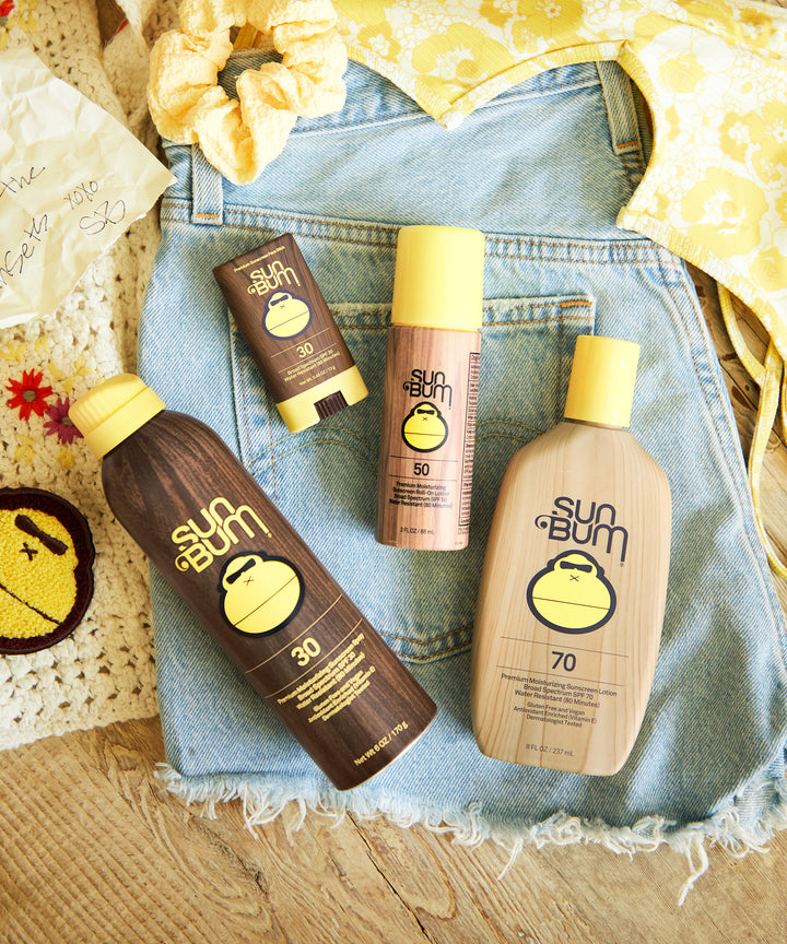 Sun Bum Original SPF 50 Sunscreen Roll-On Lotion along with other Sun Bum sunscreen products displayed on denim shorts. Sun Bum