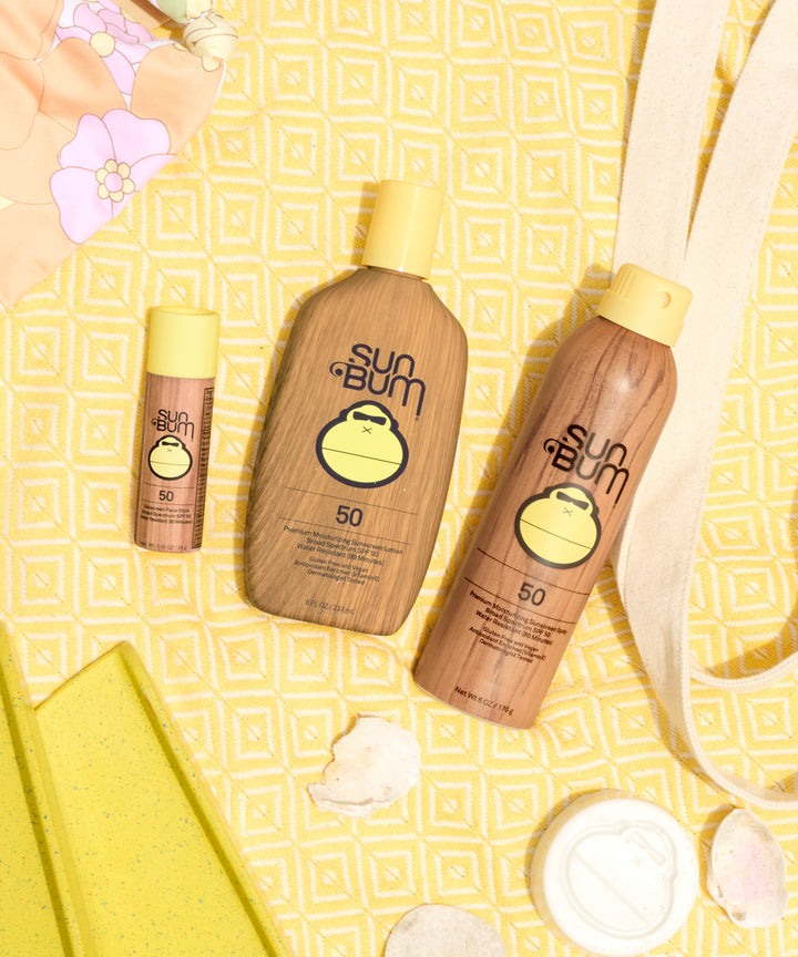 Paper Tube SPF 50 Sunscreen Face Stick by Sun Bum displayed along with other Sun Bum sunscreen products against a summer-themed background.